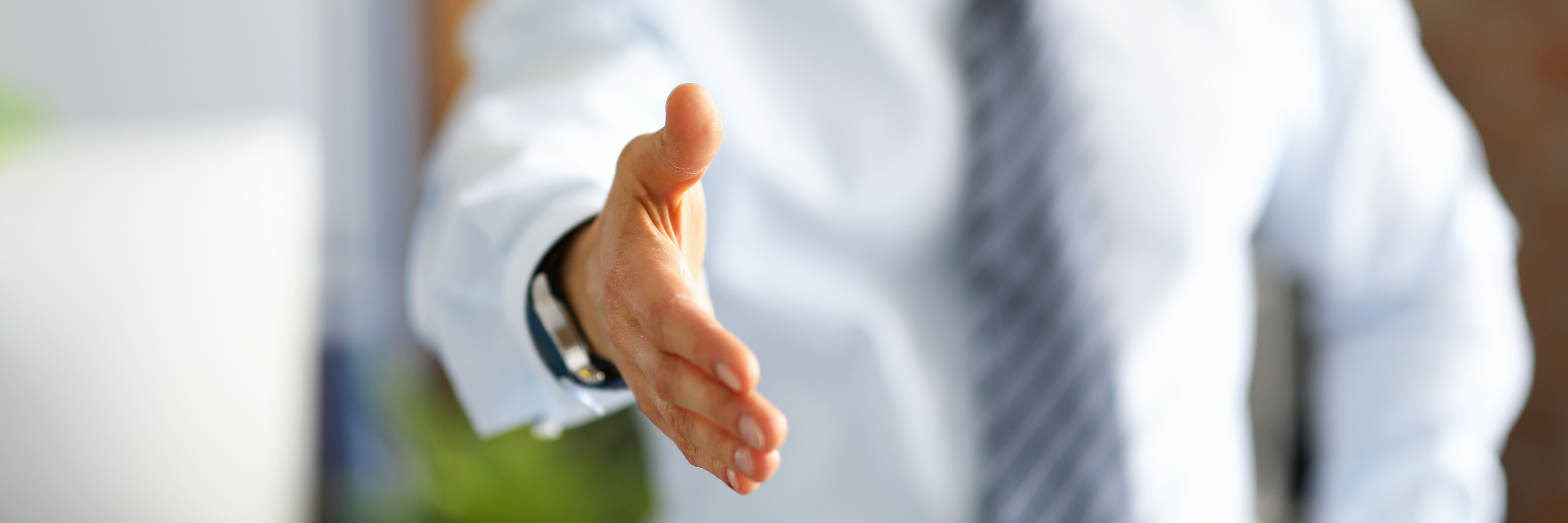 A man in business clothes holds out his hand for a greeting. Office employee meets colleagues